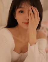 阳光洒满卧室，女孩身着丝质睡裙倚坐床沿，低头浅笑，发丝与裙摆都被镀上金色，宛如一幅静谧的古典油画