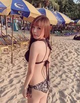 蔚蓝天空下，身着红色比基尼的女士在金色沙滩上优雅行走，裙摆随风轻扬