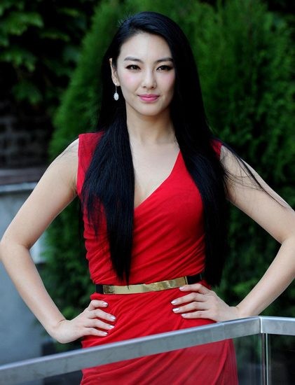 张雨绮身着白色露肩长裙侧坐于沙发，手持画笔凝望画板，窗外光线勾勒出其优雅侧影与专注神情