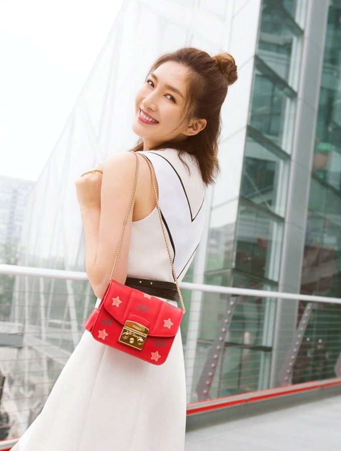 江疏影侧身面对聚光灯，细汗点缀锁骨，绸缎裙裾与光影交织，散发出充满张力的危险美感与松弛掌控力