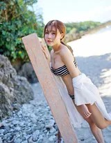 她背对镜头走向大海，条纹比基尼勾勒出优美的背部曲线，远方海天一色