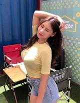 女孩坐于集装箱前，双腿自然伸展，表情惬意，展现出舒适自在的街头休闲感