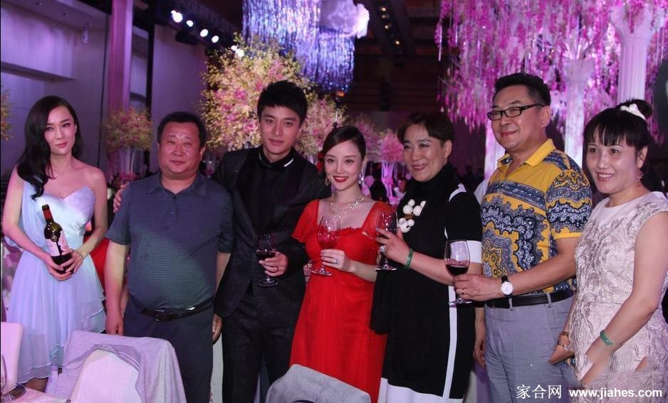 贾乃亮与李小璐身着中式礼服并肩而坐，笑容满面接受亲友祝福