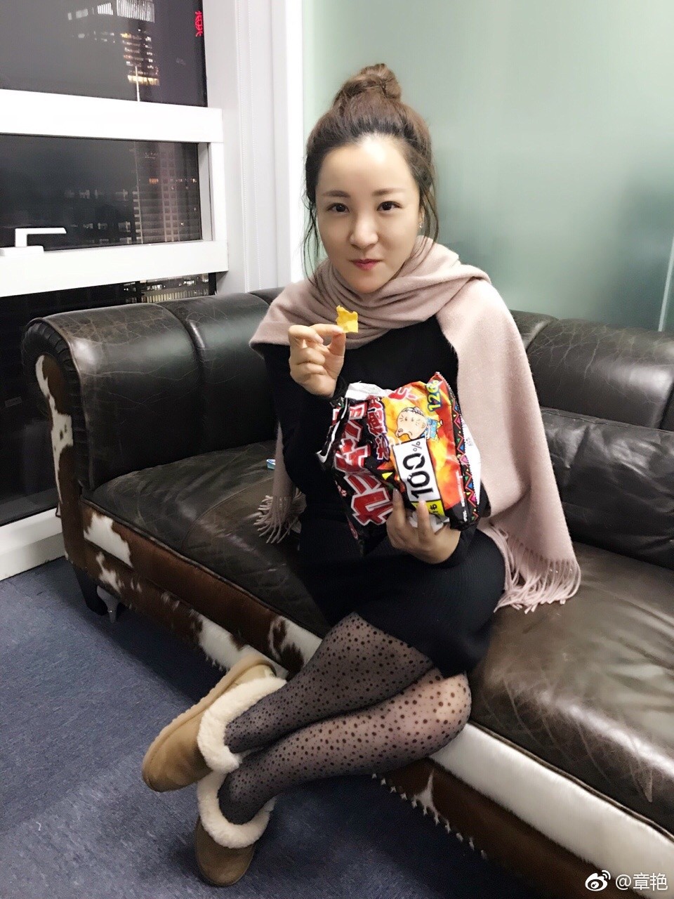 章艳身着浅色套装搭配肉色丝袜，于活动现场优雅侧立，笑容温婉展现知性风范