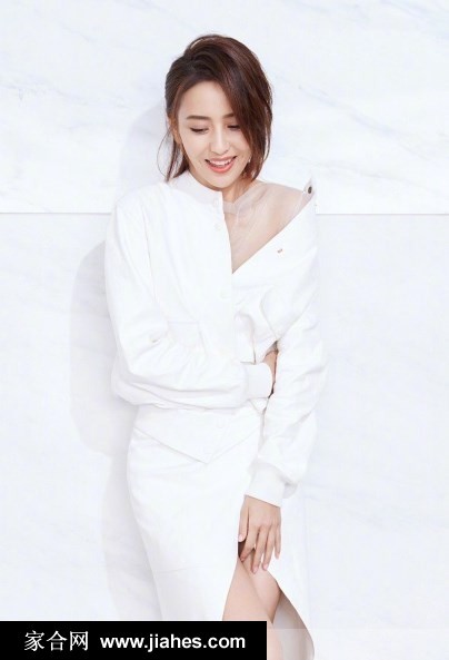 佟丽娅坐姿优雅，轻撩发丝望向镜头，条纹衬衫与精致妆容衬托知性气质