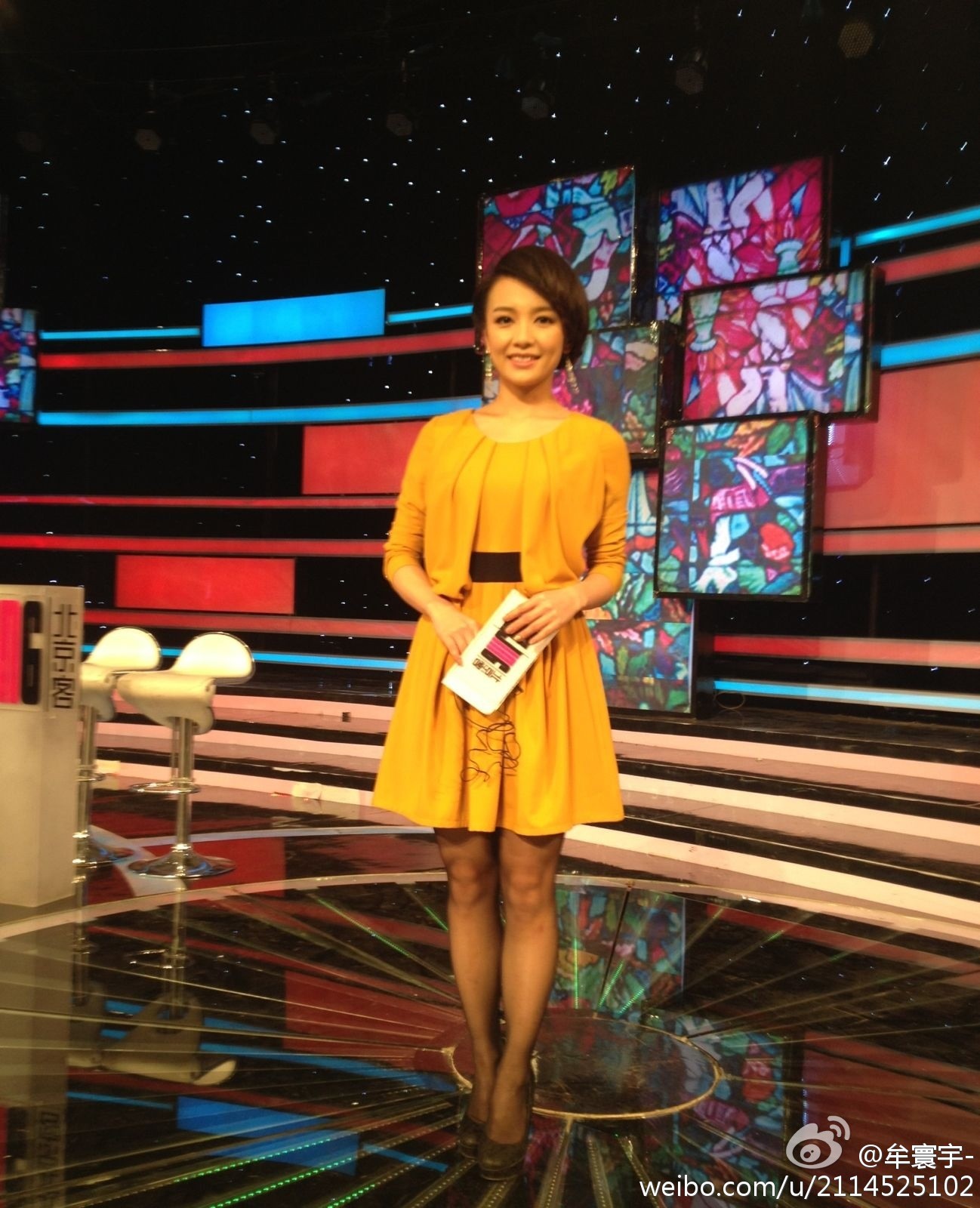 朱一静在台上从容走动，灯光洒落肩头，展现出干练与优雅并存的风范