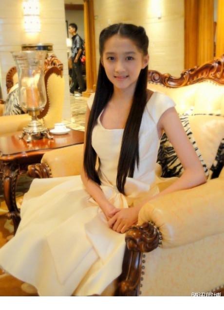 关晓彤在花园中轻捧花朵闭眼轻嗅花香，阳光透过树叶洒下斑驳光影