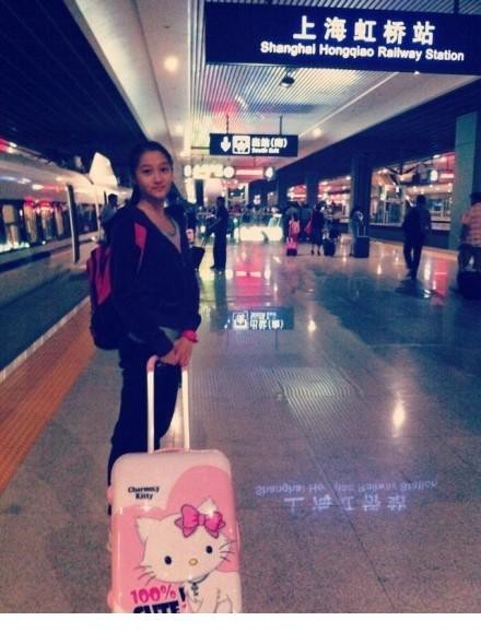 关晓彤身着白色无袖连衣裙侧身站立，领口花瓣装饰如盛开鲜花