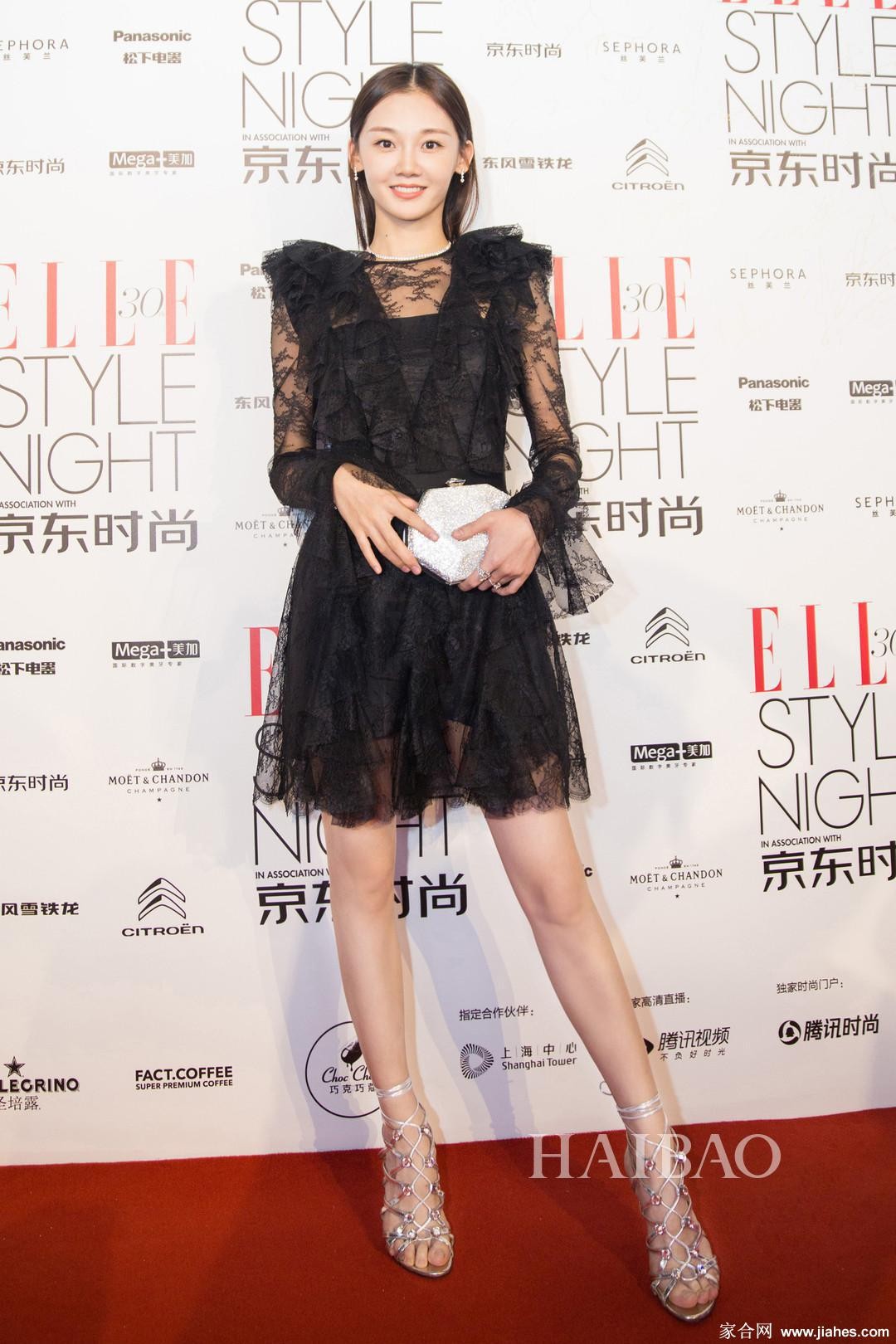 苗苗一袭优雅长裙侧身站立，灯光下丝袜微光闪烁，勾勒出纤细笔直的美腿线条