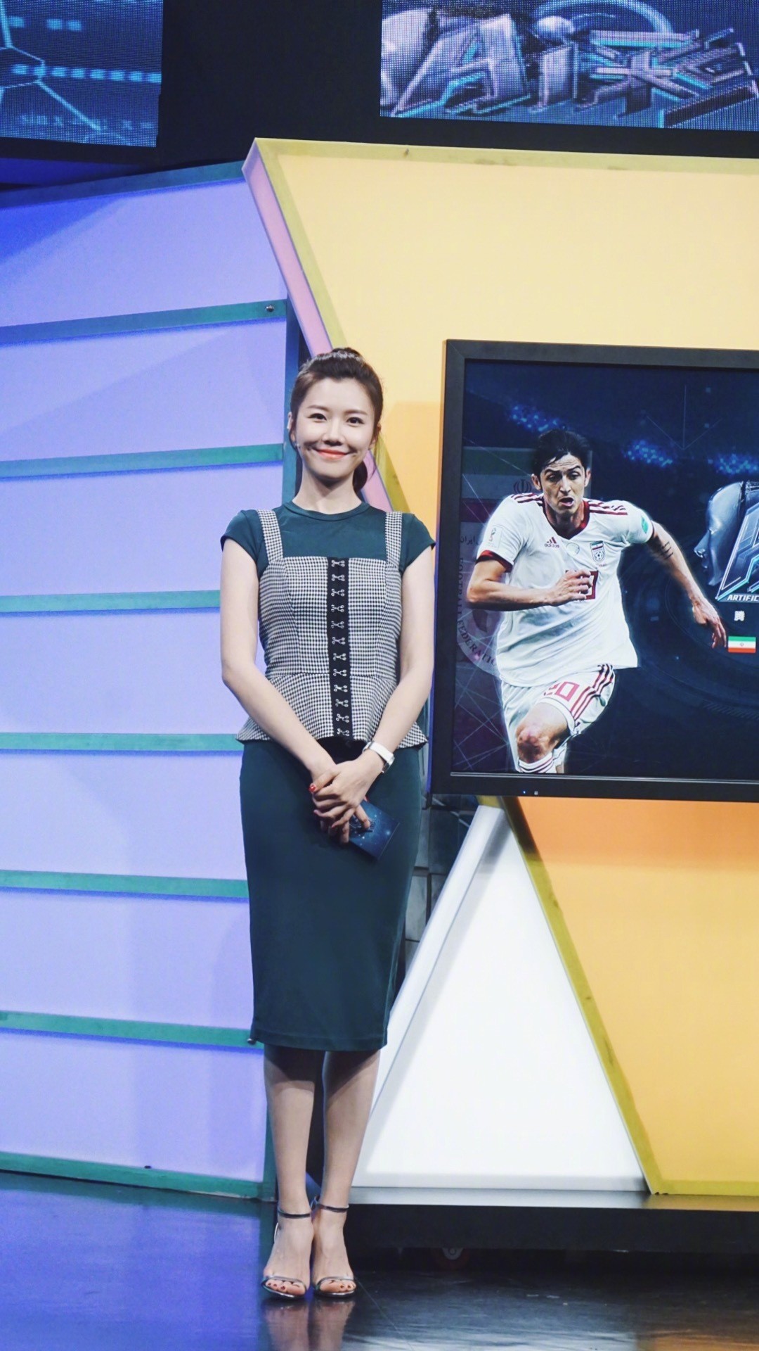 录制间隙的从容一刻，她手扶桌沿，高跟鞋与丝袜细节尽显精致态度