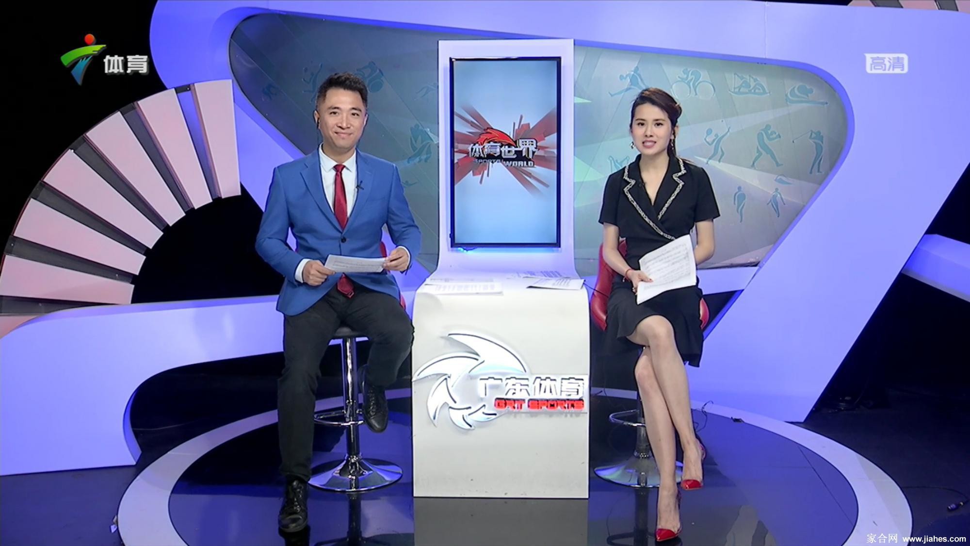 张可盈手持话筒专注主持，黑色高跟鞋衬托出专业与干练