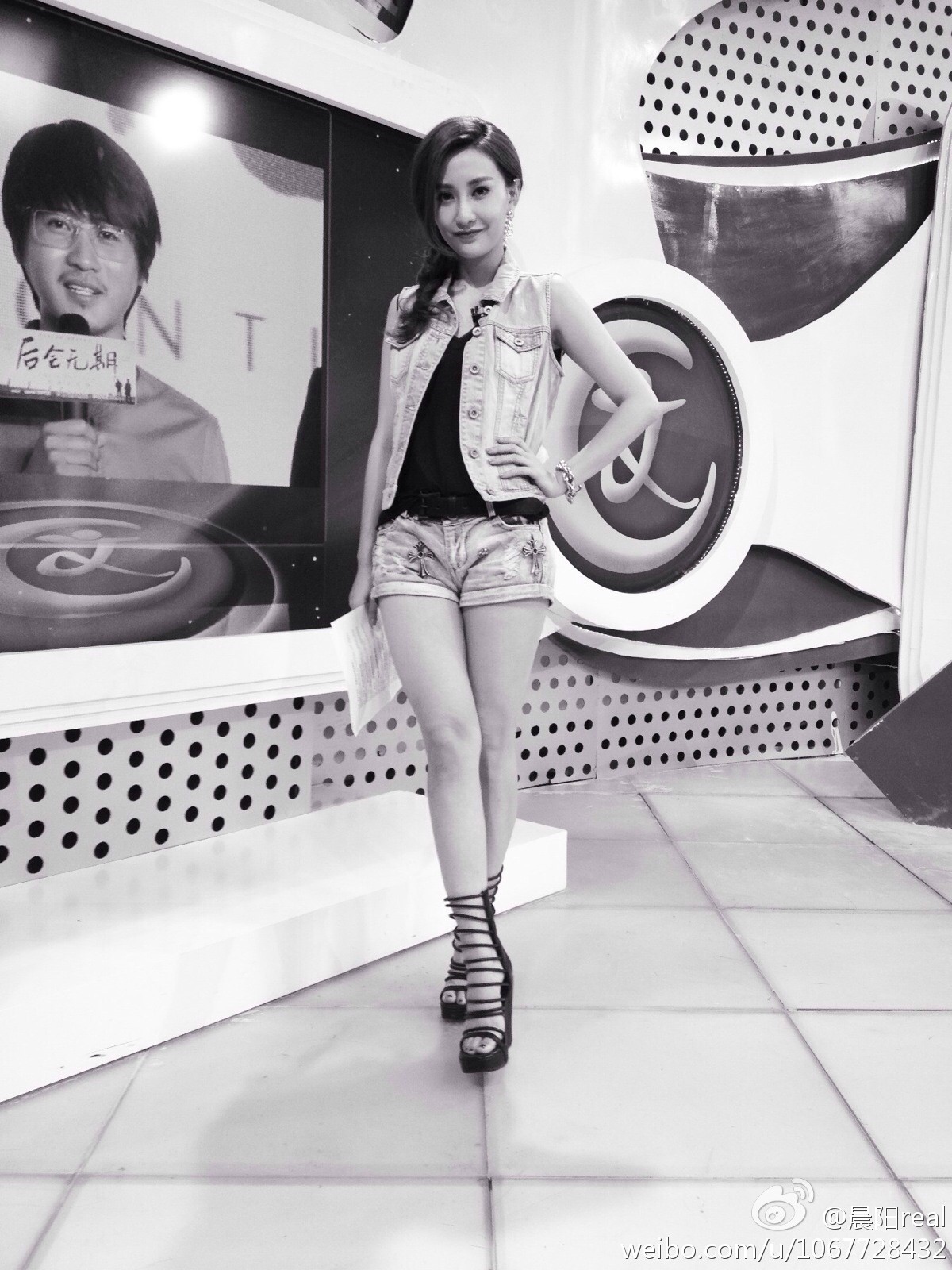 晨阳与工作人员交流时展露微笑，职业装束在后台灯光下显得格外醒目