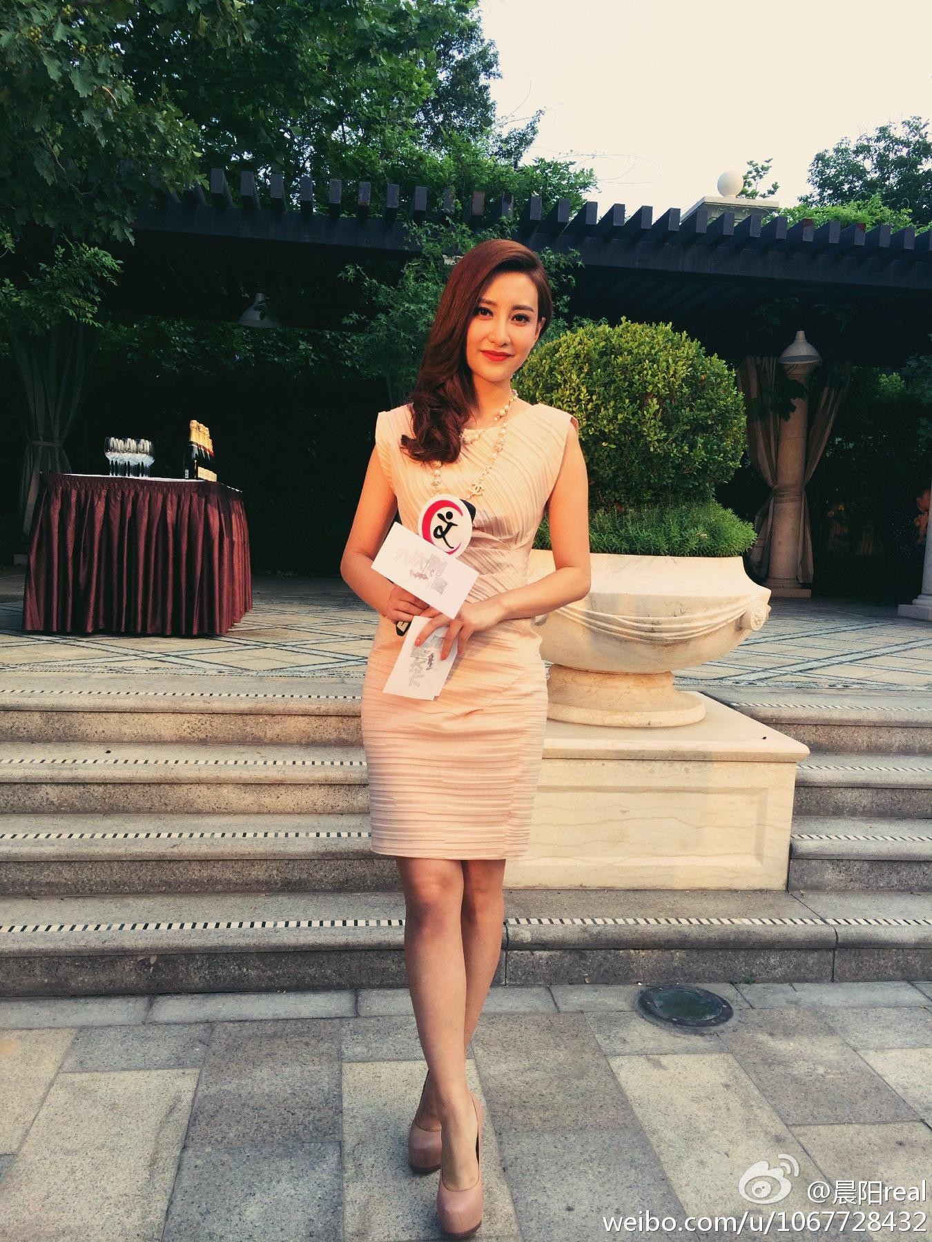 晨阳手持资料低头阅读，侧面轮廓在演播室灯光下形成优雅剪影