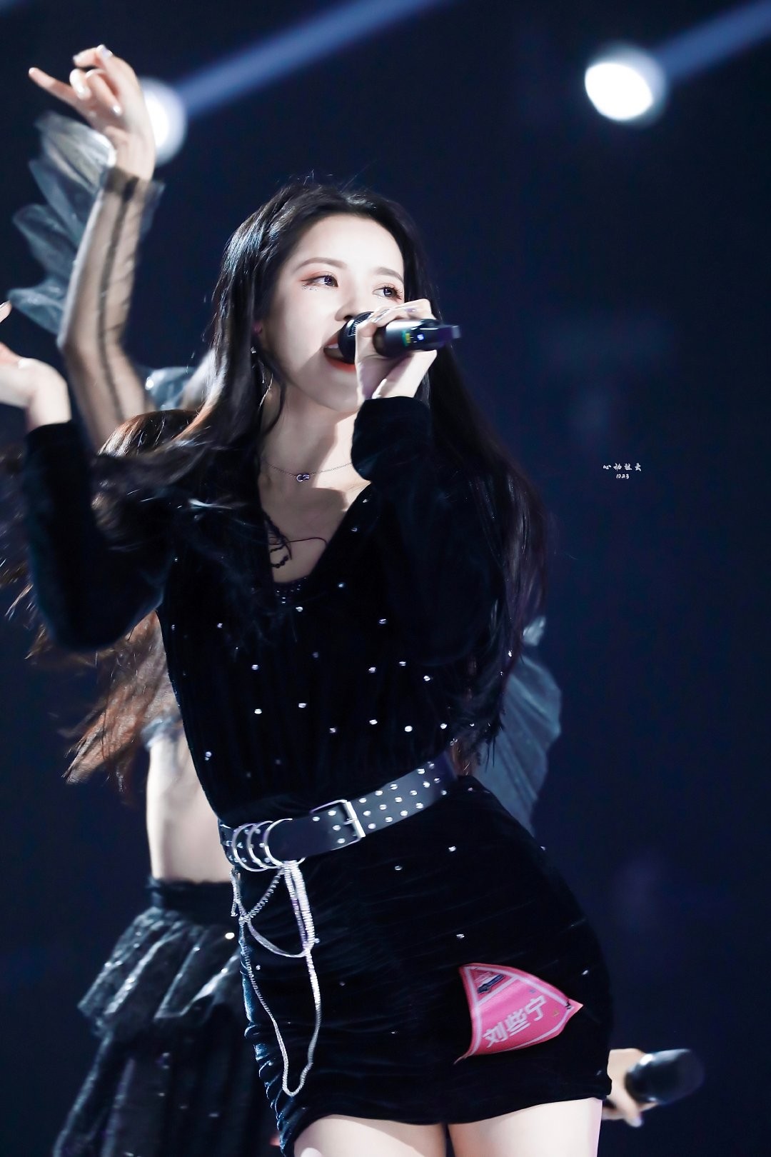 刘些宁手持话筒宛如现场焦点，裙装闪耀低调奢华光泽