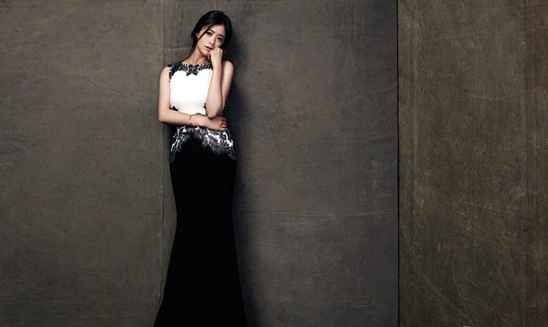 蒋欣身穿格纹长裙搭配宽檐帽，于林间光影下绽放明媚笑容，宛如油画中的少女