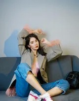 金晨倚靠于沙发，内衣与牛仔裤的搭配展现出完美的身体曲线，眼神慵懒而自信，宛如现代都市中一位掌控自我魅力的酷感女郎。