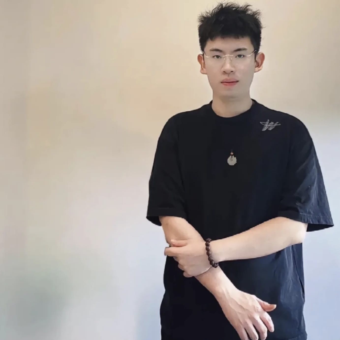 镜头前的丁祥栩，身着中式上衣，手持一件玉器，正对光线凝神细察。他表情专注而生动，背景是雅致的博古架，营造出一种介于学者书斋与电商直播间之间的独特氛围。