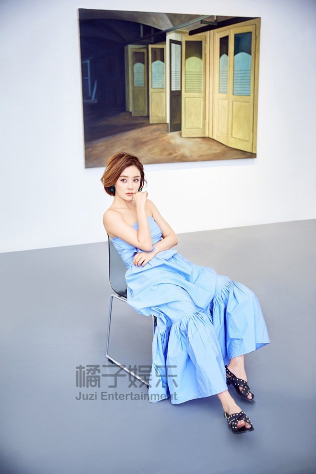 袁姗姗垂眸浅笑，蓝色裙裾如绽放的花朵，静立于光影中尽显静谧高贵