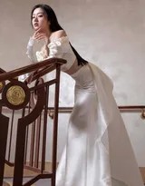 包上恩轻抚楼梯扶手，白色裙裾在阶梯间蔓延，她眼神深邃，仿佛沉浸于静谧时光