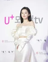 包上恩漫步楼梯间，白色长裙随步伐摇曳，她转身望向镜头，笑容清新如晨曦