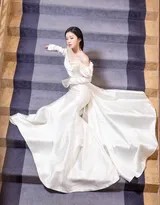 包上恩手扶栏杆缓步下行，长裙拖地如白云缭绕，她回眸一笑，尽显灵动风情