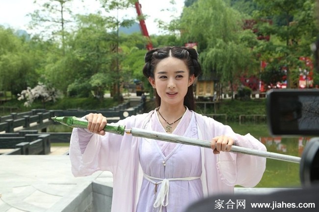 花千骨身穿浅蓝色纱裙临水而立，衣袂飘飘似仙子临凡，背景山水如墨勾勒出一幅静谧出尘的画卷