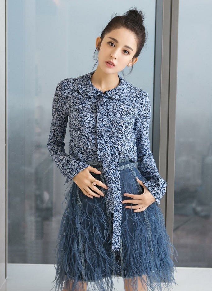 娜扎倚靠窗边目光澄澈，米色短裙与柔和光线共绘静谧画面