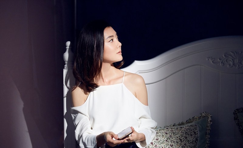 车晓长发随风微扬，单手插兜姿态潇洒，于静谧背景前展露独立自信风采