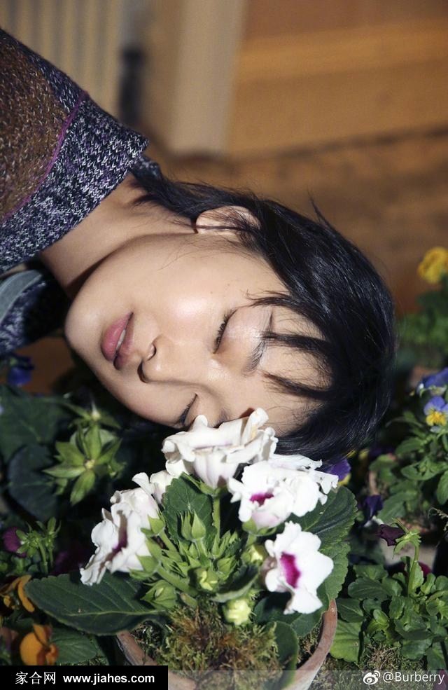 周冬雨倚靠墙面，茧型大衣的利落剪裁与柔和神态形成鲜明对比