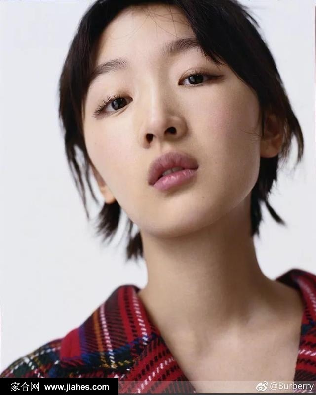 周冬雨侧身凝望，浅色茧型大衣于光影间勾勒出静谧柔和的轮廓