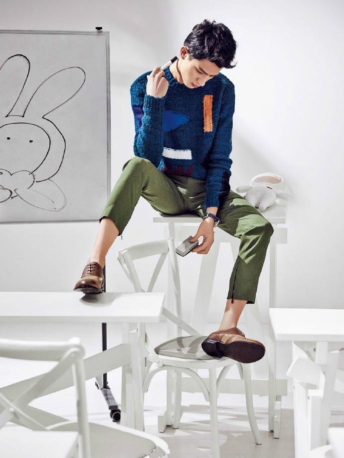 周迅身着宽松针织衫与短裙，赤足蹲坐在林中横倒的树干上，笑容舒展露出牙龈，耳畔红珠耳坠随风轻动