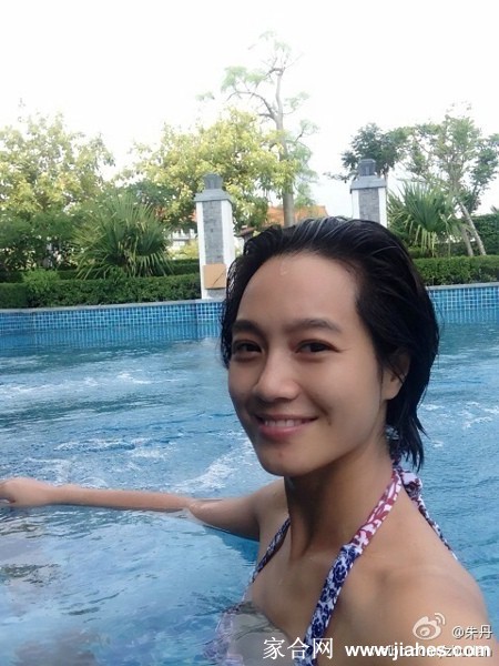 朱丹身穿优雅白色长裙，在阳光下侧身浅笑，裙摆飘逸，尽显纯静甜美气质