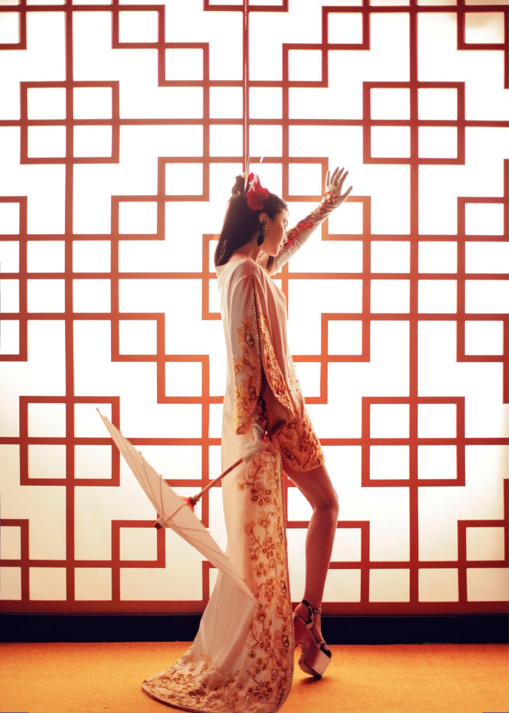 范冰冰侧身回眸，金色头冠与华丽耳饰交相辉映，背景的暗红色调衬托出其如瓷器般精致的侧脸轮廓