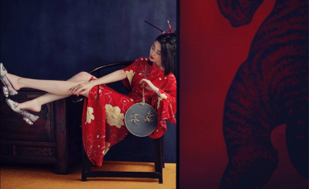 范冰冰身着大红金线刺绣礼服端坐于中央，气场全开，周身环绕的奢华织锦与她的明艳共同构筑了一幅盛世牡丹图