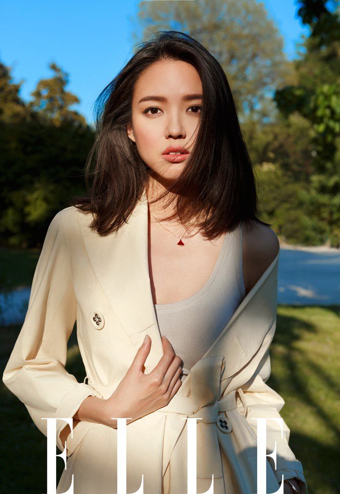 张梓琳身着米色风衣漫步于石板路上，阳光洒落肩头，尽显慵懒而高级的意式时髦