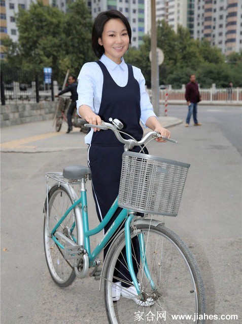 闫妮在古城墙下骑着复古自行车，笑容灿烂如阳光