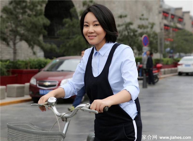 闫妮漫步于古朴砖墙前，步履轻盈身影与历史背景构成和谐画面