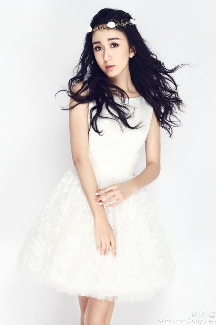 娄艺潇身着白色纱裙侧身凝望，眼神清澈似水，飘逸裙摆宛如绽放的花朵