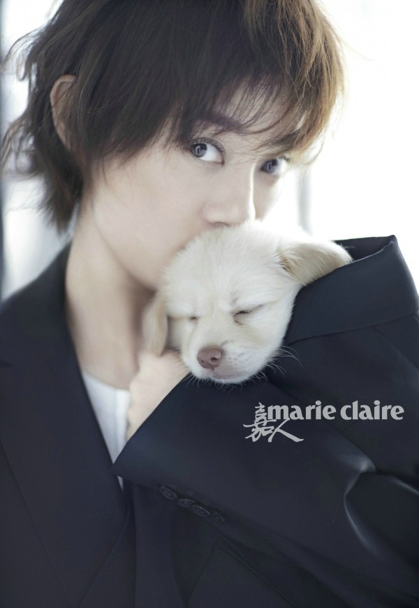 孙俪身着浅色宽松西装，眼神温柔地低头轻抚怀中乖巧的白色小狗