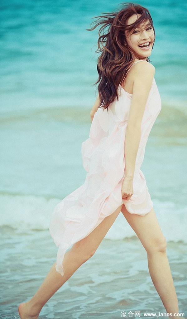 碧海晴空下，张俪开心挥手，身后是湛蓝海水与白色游艇，充满度假的欢愉