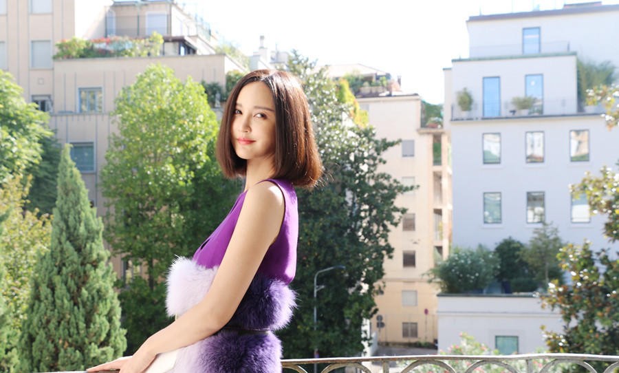 张歆艺身穿黑色短T恤与丹宁外套，倚靠纽约街头的电线杆，笑容自信洒脱