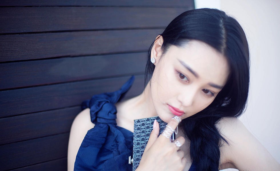 张馨予双手轻举撩动如瀑长发，在简约背景前展现随性而不失高级的自信气场