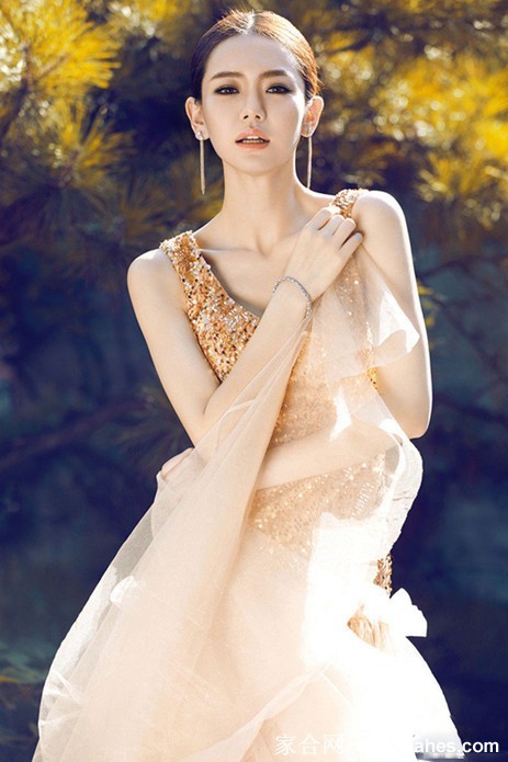 戚薇身着深蓝抹胸长裙侧身回望，慵懒卷发垂落于凌厉肩颈