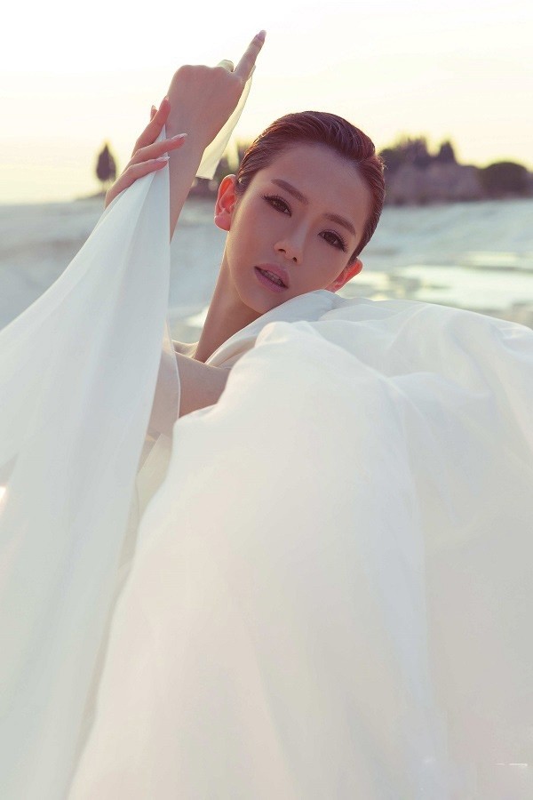 戚薇仰首闭目感受微风，颈项线条优雅，头顶白纱轻覆如披月华