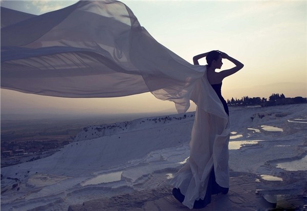 戚薇垂眸浅笑，双手轻抚胸前纱襟，柔和光线映照出细腻肌肤与纱裙纹理