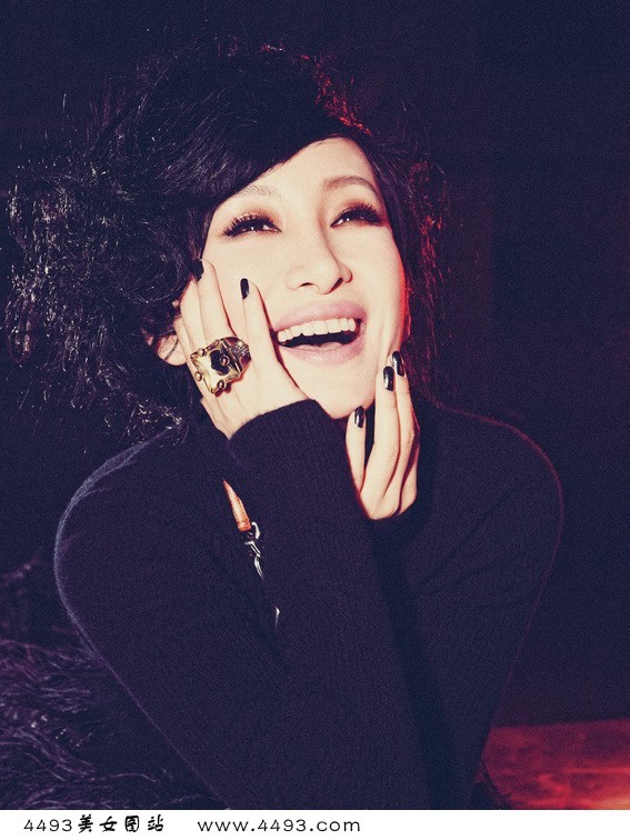 秦海璐身着黑色长裙侧身而立，肩颈线条流畅优雅，灯光下肌肤胜雪，回眸间尽显冷艳神秘的高贵气场。