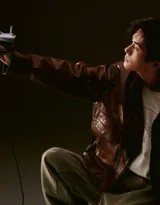 易烊千玺背影行走，皮衣与工装牛仔裤勾勒出挺拔身形，随身听耳机线随风轻摆，仿佛在都市中独行