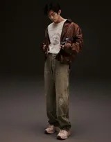 易烊千玺在斑驳墙面前站立，皮衣与工装牛仔裤色彩对比鲜明，随身听成为焦点，整体画面充满故事感