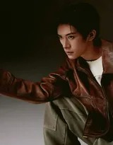 易烊千玺半身特写，皮衣拉链微开露出内搭，随身听耳机贴近耳廓，眼神坚定中带着柔和复古韵味