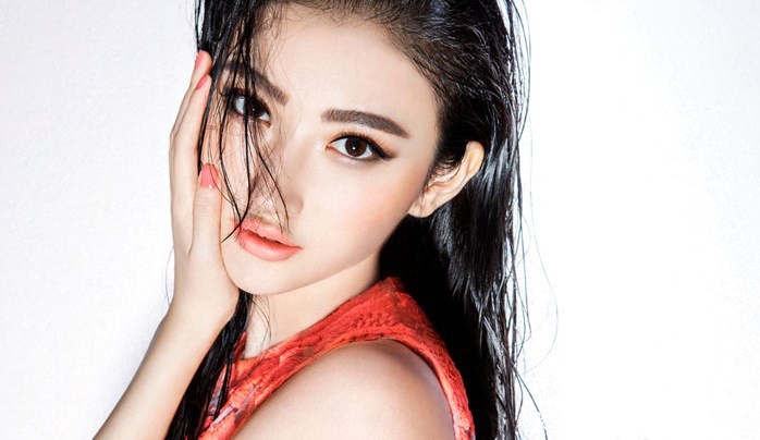 景甜倚靠窗边眼神温柔，橘色毛衣映衬出温暖宁静的午后氛围